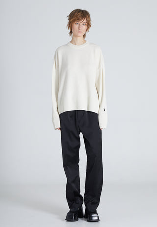 Woman is wearing a white cashmere sweater and black pants on a light gray background