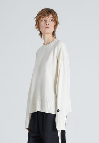 Woman wearing white cashmere crewneck. She is also wearing black trousers. 