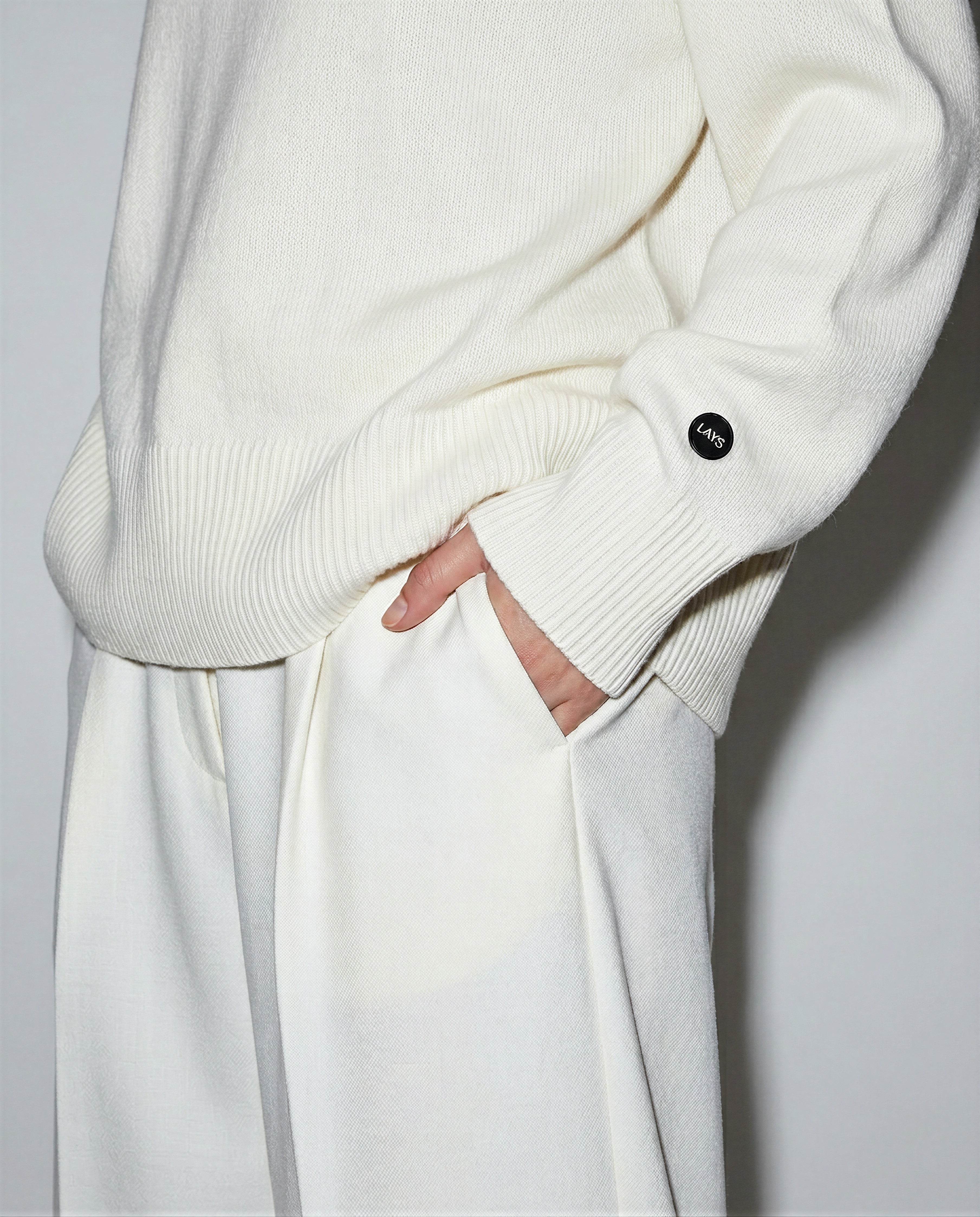 White sweater and pants worn by a person on a plain background