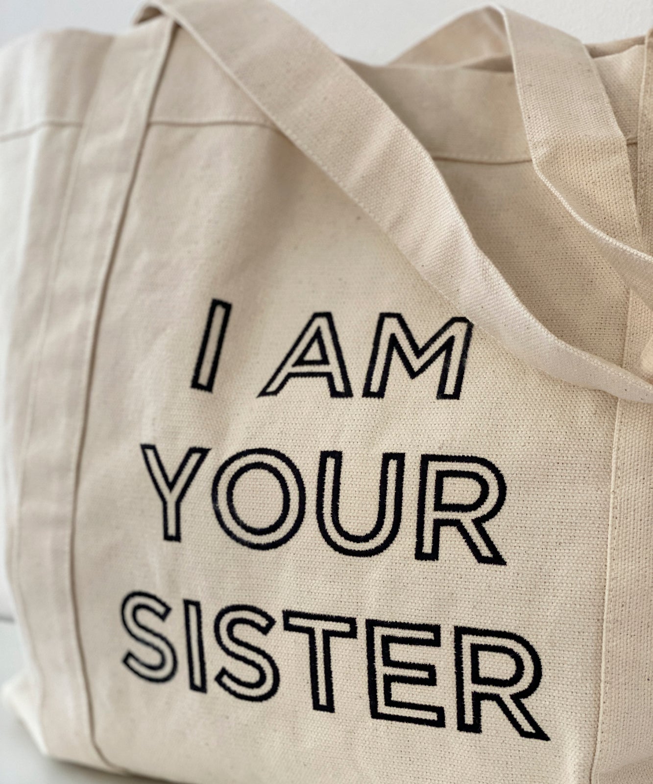 Close up of embroidered statement I AM YOUR SISTER
